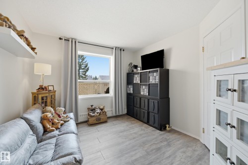 Light-toned wood-finish flooring provides a neutral backdrop for the room's white walls - #208 9760 176 St Nw, Edmonton, AB - Indoor