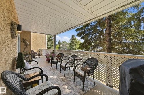 Spacious covered balcony featuring a textured stucco exterior wall, louvered ceiling, and decorative lattice railing - #208 9760 176 St Nw, Edmonton, AB - Outdoor With Deck Patio Veranda With Exterior