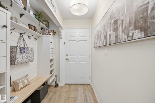 Entryway featuring a built-in bench, shiplap accent wall, and wood-finish flooring - #208 9760 176 St Nw, Edmonton, AB - Indoor Photo Showing Other Room