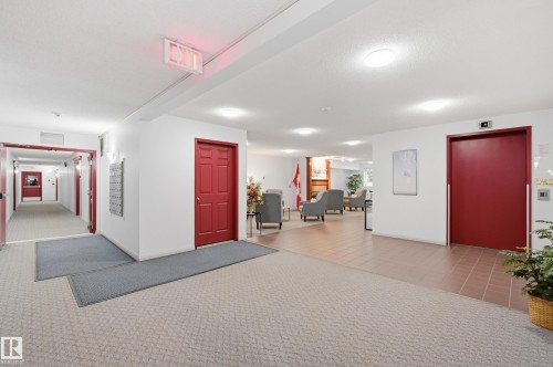 Spacious common area featuring recessed lighting, a combination of carpeting and tile flooring, and a lounge area with armchairs - #208 9760 176 St Nw, Edmonton, AB - Indoor Photo Showing Other Room