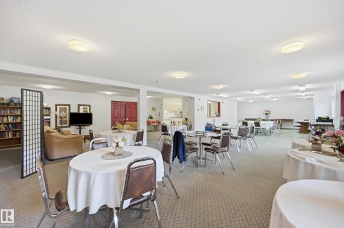 Expansive common area featuring neutral carpeting, a variety of seating arrangements, and overhead lighting - #208 9760 176 St Nw, Edmonton, AB - Indoor Photo Showing Dining Room