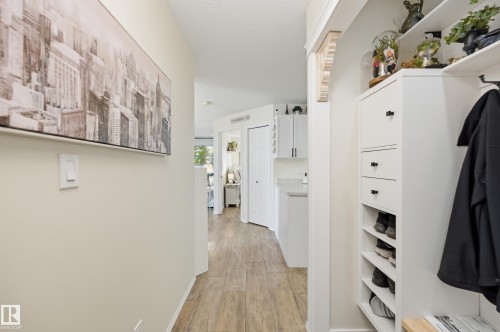 Hallway featuring wood-finish flooring, light-toned walls, and white baseboards - #208 9760 176 St Nw, Edmonton, AB - Indoor Photo Showing Laundry Room
