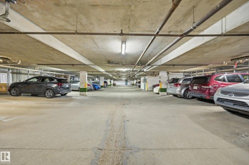 Underground parking garage featuring concrete flooring, concrete ceiling, fluorescent lighting, and visible utility conduits - #208 9760 176 St Nw, Edmonton, AB - Indoor Photo Showing Garage