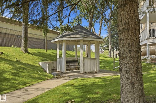 White gazebo with a shingled roof and built-in slatted bench seating - #208 9760 176 St Nw, Edmonton, AB - Outdoor