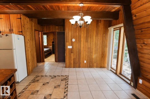 Dining area featuring wood-paneled walls and ceiling, a classic chandelier, and light-toned tile flooring with a decorative inset - 329 60417 Range Road 124, Rural St. Paul County, AB - Indoor