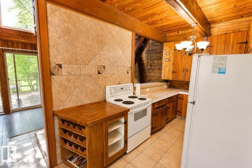 Kitchen featuring wood-paneled walls and ceiling, tile flooring, and a decorative tile backsplash - 329 60417 Range Road 124, Rural St. Paul County, AB - Indoor Photo Showing Kitchen