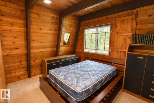 Interior room featuring natural wood paneling, exposed wood beams, and a window with security bars - 329 60417 Range Road 124, Rural St. Paul County, AB - Indoor Photo Showing Bedroom