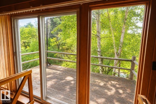 Sliding glass doors opening to an exterior wood-finish deck with a rustic wood railing - 329 60417 Range Road 124, Rural St. Paul County, AB - Indoor Photo Showing Other Room