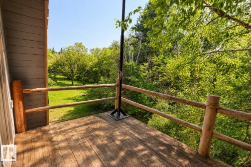 Outdoor wood-finish deck with natural wood railing, surrounded by mature trees and verdant foliage - 329 60417 Range Road 124, Rural St. Paul County, AB - Outdoor With Exterior