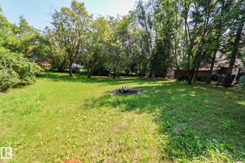 Expansive grassy area featuring mature trees and a dedicated fire pit - 329 60417 Range Road 124, Rural St. Paul County, AB - Outdoor
