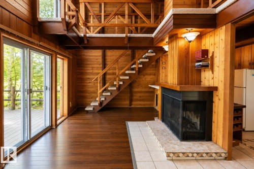 Spacious living area featuring wood-finish flooring and extensive natural wood paneling - 329 60417 Range Road 124, Rural St. Paul County, AB - Indoor With Fireplace