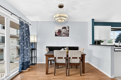 Dining area featuring wood-finish flooring, a contemporary chandelier, and a sliding glass door - #72 2505 42 St Nw, Edmonton, AB - Indoor Photo Showing Dining Room
