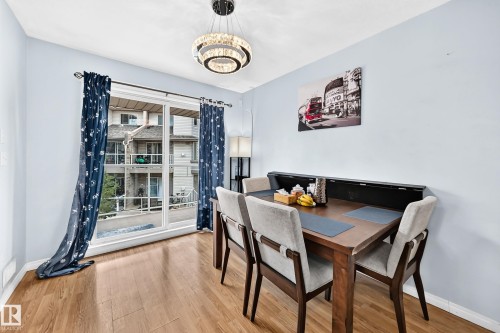 Dining area featuring wood-finish flooring, a large sliding glass door, a contemporary chandelier, and light blue walls - #72 2505 42 St Nw, Edmonton, AB - Indoor Photo Showing Dining Room