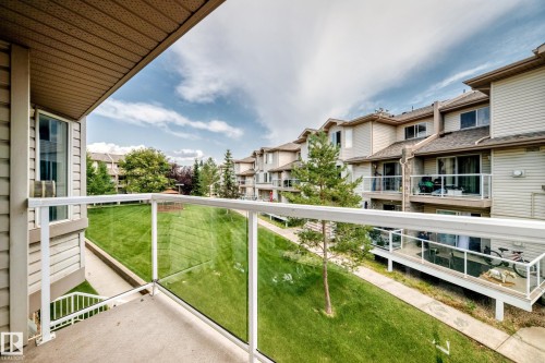 Private balcony featuring a glass panel railing system, concrete flooring, and a neutral-toned vinyl soffit - #72 2505 42 St Nw, Edmonton, AB - Outdoor With Exterior