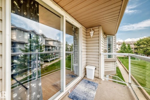 Private balcony featuring glass panel railings, tan siding, and a sliding glass door - #72 2505 42 St Nw, Edmonton, AB - Outdoor With Exterior