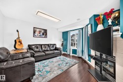 Living area featuring dark wood-finish flooring, a contemporary rectangular ceiling light fixture, and a bay window with natural light - 