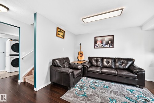 Dark wood-finish flooring complements light-colored walls in this space featuring a built-in overhead light fixture - #72 2505 42 St Nw, Edmonton, AB - Indoor Photo Showing Living Room