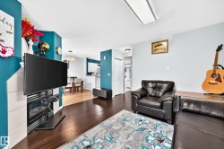 Living area featuring wood-finish flooring, a corner fireplace with light-toned tile surround, and a ceiling-mounted light fixture - 