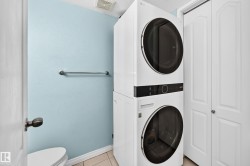 White stackable washer and dryer unit with front-loading design, complemented by a nearby two-panel white bifold closet door - 