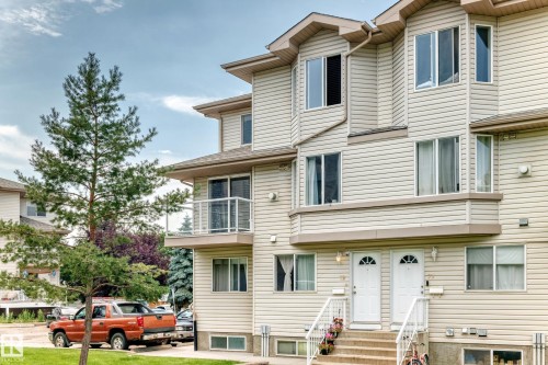 Multi-level exterior featuring light-toned horizontal siding, bay windows, and individual entryways - #72 2505 42 St Nw, Edmonton, AB - Outdoor