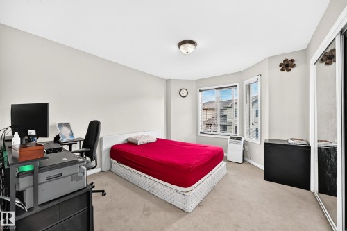 Bedroom featuring a bay window, neutral wall tones, carpeted flooring, a flush-mount ceiling light fixture, and mirrored closet doors - #72 2505 42 St Nw, Edmonton, AB - Indoor
