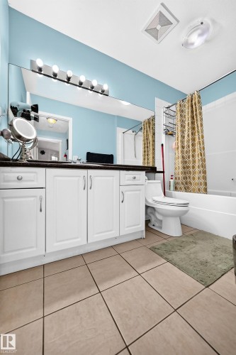 Bathroom featuring a white vanity with dark countertop, large wall-mounted mirror, overhead vanity lighting, white bathtub, and tile flooring - #72 2505 42 St Nw, Edmonton, AB - Indoor Photo Showing Bathroom