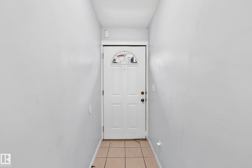 Entryway featuring a paneled door with an arched glass insert, light-colored tile flooring, and neutral wall finishes - #72 2505 42 St Nw, Edmonton, AB - Indoor Photo Showing Other Room
