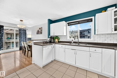Contemporary kitchen featuring white cabinetry, dark countertops, and a subway tile backsplash - #72 2505 42 St Nw, Edmonton, AB - Indoor Photo Showing Kitchen With Double Sink