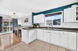 Contemporary kitchen featuring white cabinetry, dark countertops, and a subway tile backsplash - 