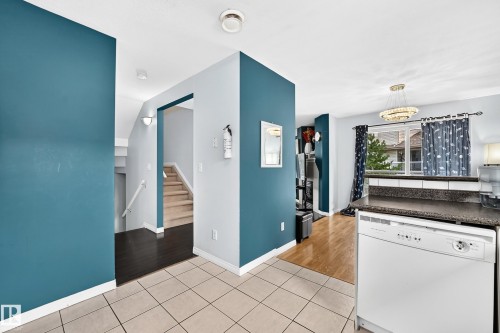 Kitchen area featuring a white dishwasher, dark countertop, and tiled flooring - #72 2505 42 St Nw, Edmonton, AB - Indoor