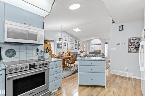 Modern kitchen with light blue cabinetry and stainless steel appliances - #12 64 Blackburn Dr W Sw, Edmonton, AB - Indoor Photo Showing Kitchen