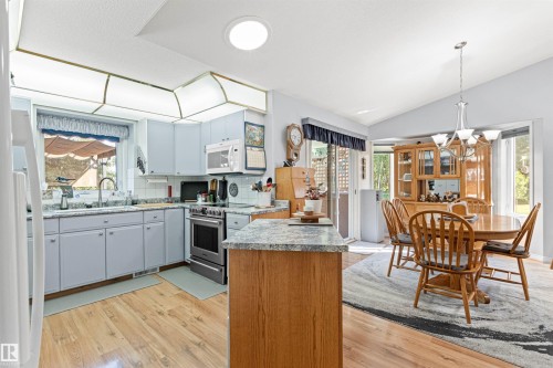 Kitchen featuring light blue cabinetry, granite-style countertops, stainless steel appliances, and wood-finish flooring - #12 64 Blackburn Dr W Sw, Edmonton, AB - Indoor