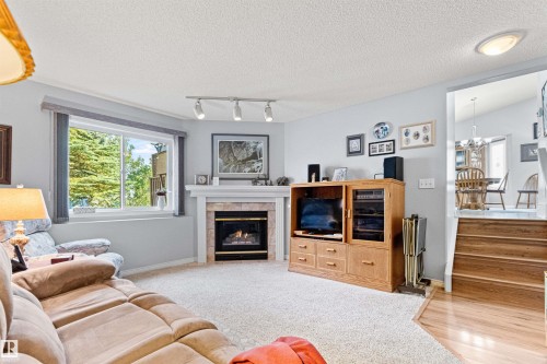 Corner fireplace with a tile surround and white mantel - #12 64 Blackburn Dr W Sw, Edmonton, AB - Indoor Photo Showing Living Room With Fireplace