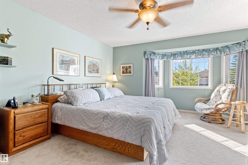 Spacious Primary Bedroom featuring light blue walls, soft carpet flooring, and a multi-pane bay window - #12 64 Blackburn Dr W Sw, Edmonton, AB - Indoor Photo Showing Bedroom