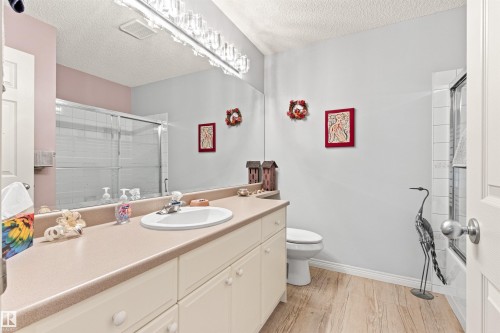 Vanity featuring an integrated sink with chrome faucet, light-toned countertop, and white cabinetry - #12 64 Blackburn Dr W Sw, Edmonton, AB - Indoor Photo Showing Bathroom