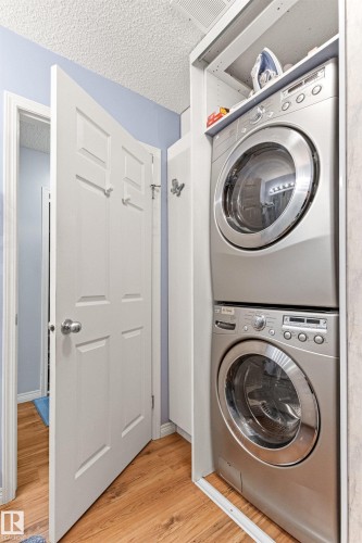 Dedicated laundry area featuring stacked front-load washer and dryer units - #12 64 Blackburn Dr W Sw, Edmonton, AB - Indoor Photo Showing Laundry Room