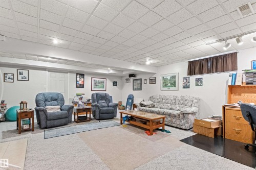 Spacious room featuring light coloured walls, a white acoustic panel ceiling, and a mix of light-colored carpeting. - #12 64 Blackburn Dr W Sw, Edmonton, AB - Indoor