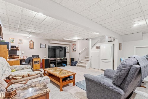 Recreation Room featuring carpeting, track lighting, a drop ceiling, and a built-in staircase - #12 64 Blackburn Dr W Sw, Edmonton, AB - Indoor