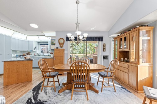 Dining area featuring wood-finish flooring, a contemporary chandelier, and a wood hutch - #12 64 Blackburn Dr W Sw, Edmonton, AB - Indoor Photo Showing Dining Room