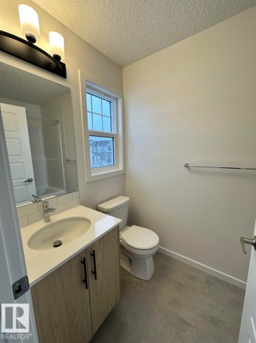 Modern vanity with a light wood-finish cabinet, white countertop, and under-mount sink - 22803 94 Anenue Northwest, Edmonton, AB - Indoor Photo Showing Bathroom