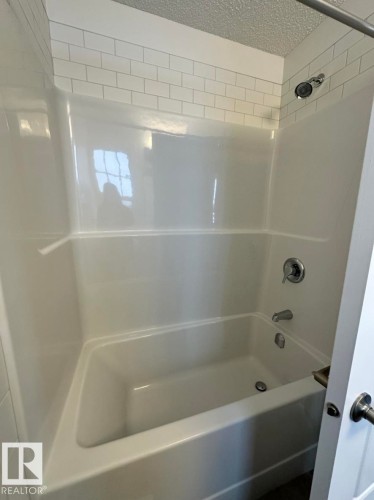 Bathtub with white subway tile surround, chrome fixtures, and integrated shelving - 22803 94 Anenue Northwest, Edmonton, AB - Indoor Photo Showing Bathroom