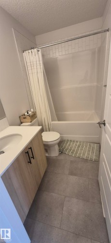 Bathroom featuring a full-size bathtub with subway tile surround, a single vanity with stone-finish countertop, and large format tile flooring - 22803 94 Anenue Northwest, Edmonton, AB - Indoor Photo Showing Bathroom