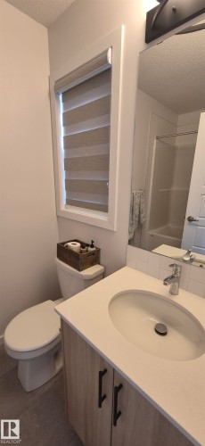 Vanity with integrated sink, white countertop, and light wood-finish cabinetry featuring matte black hardware - 22803 94 Anenue Northwest, Edmonton, AB - Indoor Photo Showing Bathroom