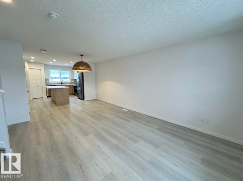 Open-concept living area featuring light wood-finish flooring, recessed ceiling lighting, and a contemporary pendant light fixture - 22803 94 Anenue Northwest, Edmonton, AB - Indoor Photo Showing Other Room