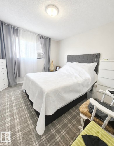 Bright interior space featuring a window with privacy blinds, wood-finish flooring, and a flush-mount ceiling light - 3236 27 Avenue Nw, Edmonton, AB - Indoor Photo Showing Bedroom