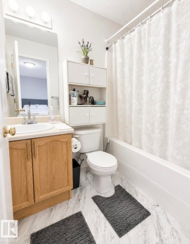 Bathroom featuring a white bathtub, toilet, and a vanity with a light wood-finish cabinet and white countertop - 3236 27 Avenue Nw, Edmonton, AB - Indoor Photo Showing Bathroom