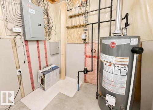 Utility area featuring a Rheem water heater, electrical panel, PEX manifold system, and concrete flooring - 3236 27 Avenue Nw, Edmonton, AB - Indoor Photo Showing Basement