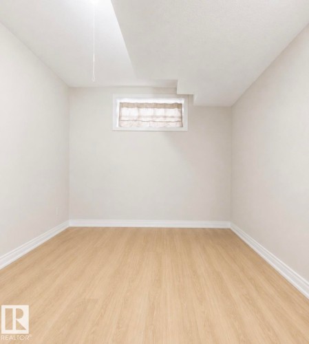 Light wood-finish flooring with crisp white baseboards and neutral wall tones - 3236 27 Avenue Nw, Edmonton, AB - Indoor Photo Showing Other Room