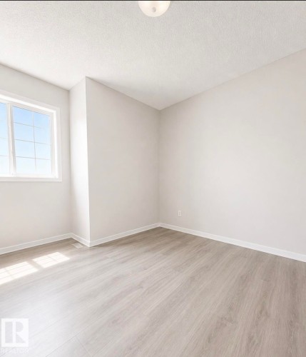 Bright room featuring light wood-finish flooring, neutral paint palette, ample natural light from a multi-pane window, and a ceiling-mounted light fixture - 3236 27 Avenue Nw, Edmonton, AB - Indoor Photo Showing Other Room