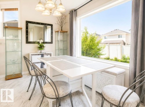 Dining area featuring a large picture window, a neutral color palette, and wood-finish flooring - 3236 27 Avenue Nw, Edmonton, AB - Indoor Photo Showing Dining Room